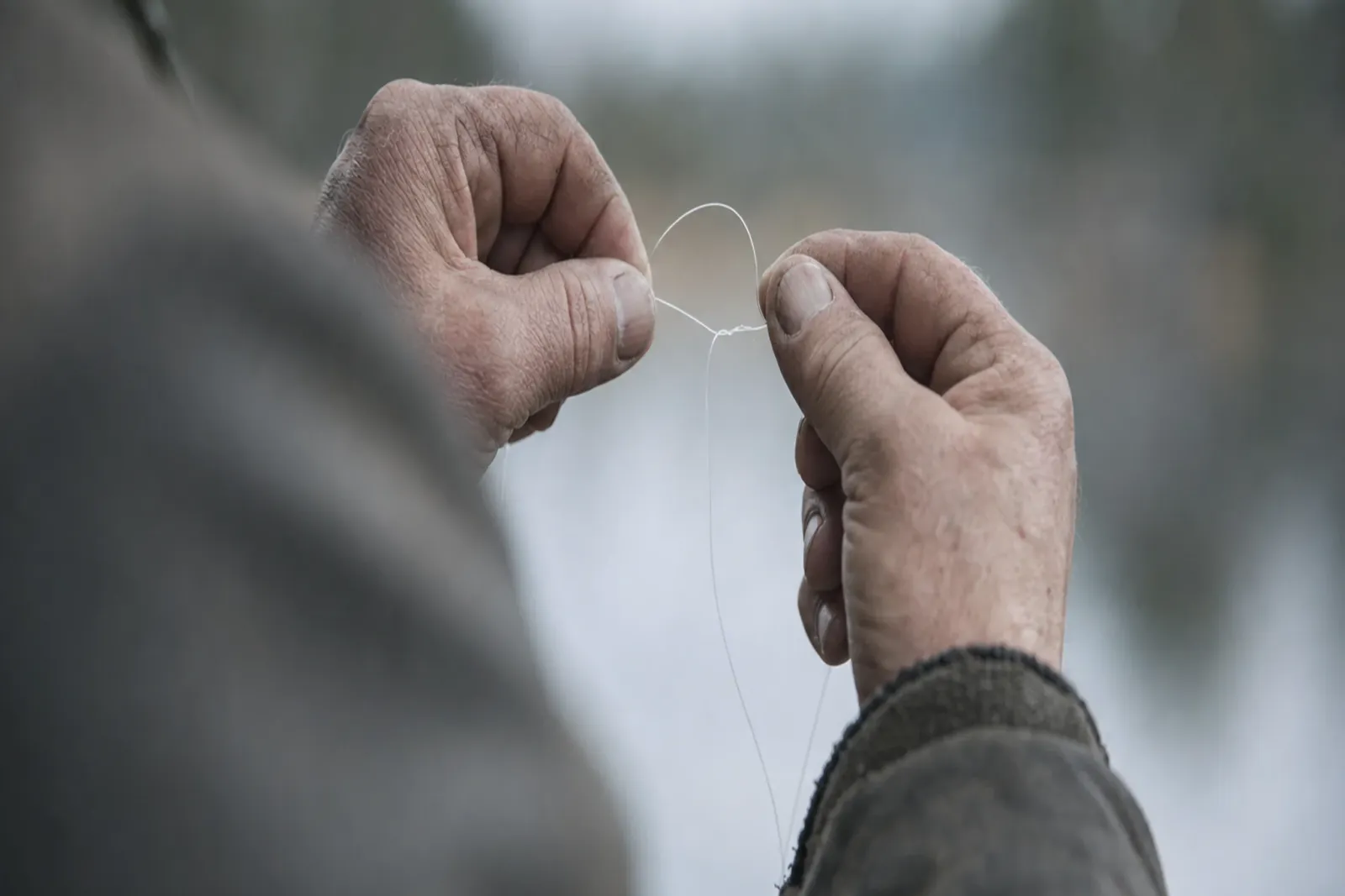 Händer som knyter en knop på en fiskelina